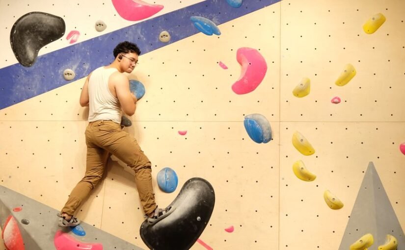 Suaugęs laipiotojas įveikia ryškią boulderingo sienelę – puiki pramoga visiems